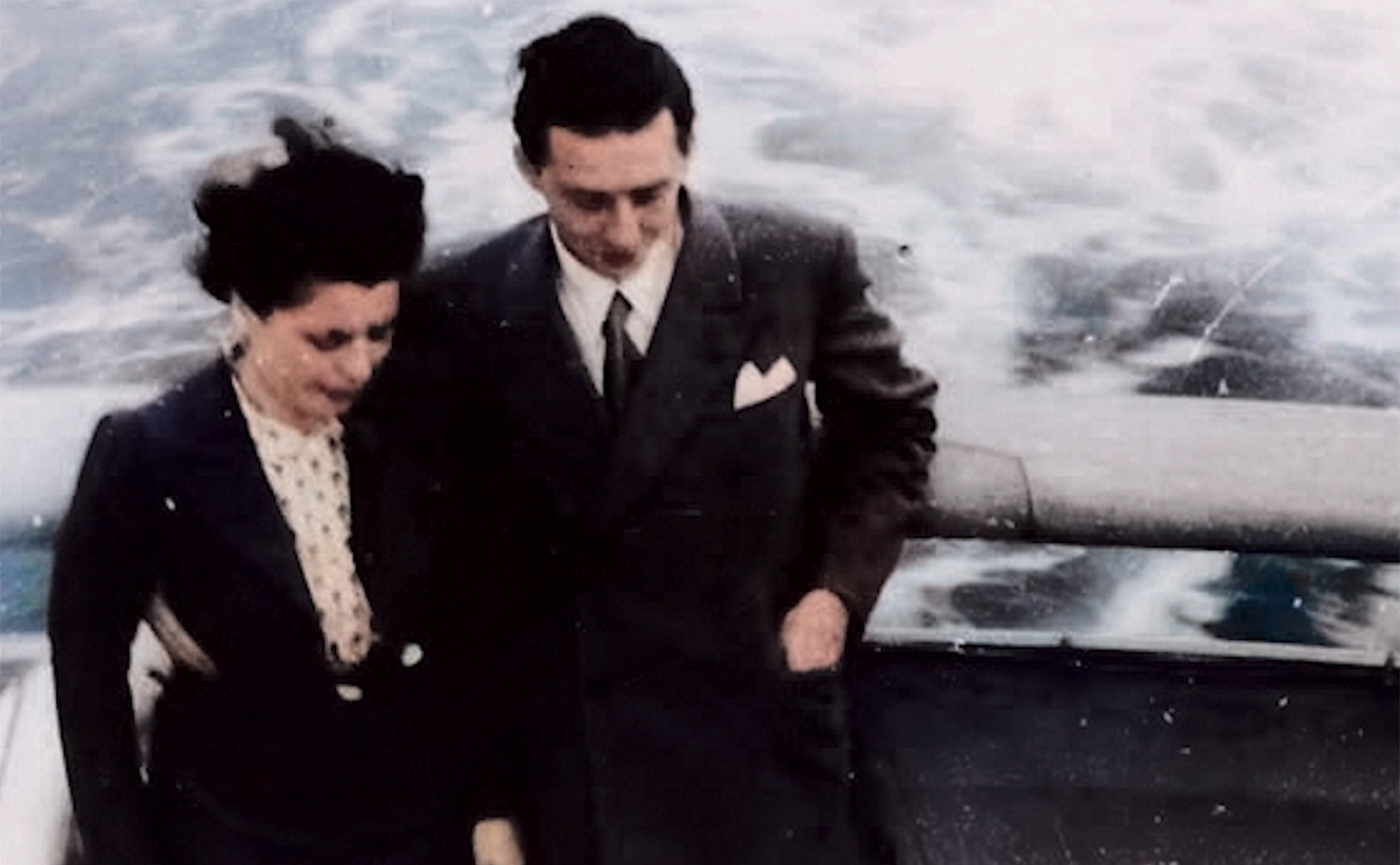 sailboat floating past craggy gray rocks on a stormy ocean in greenland