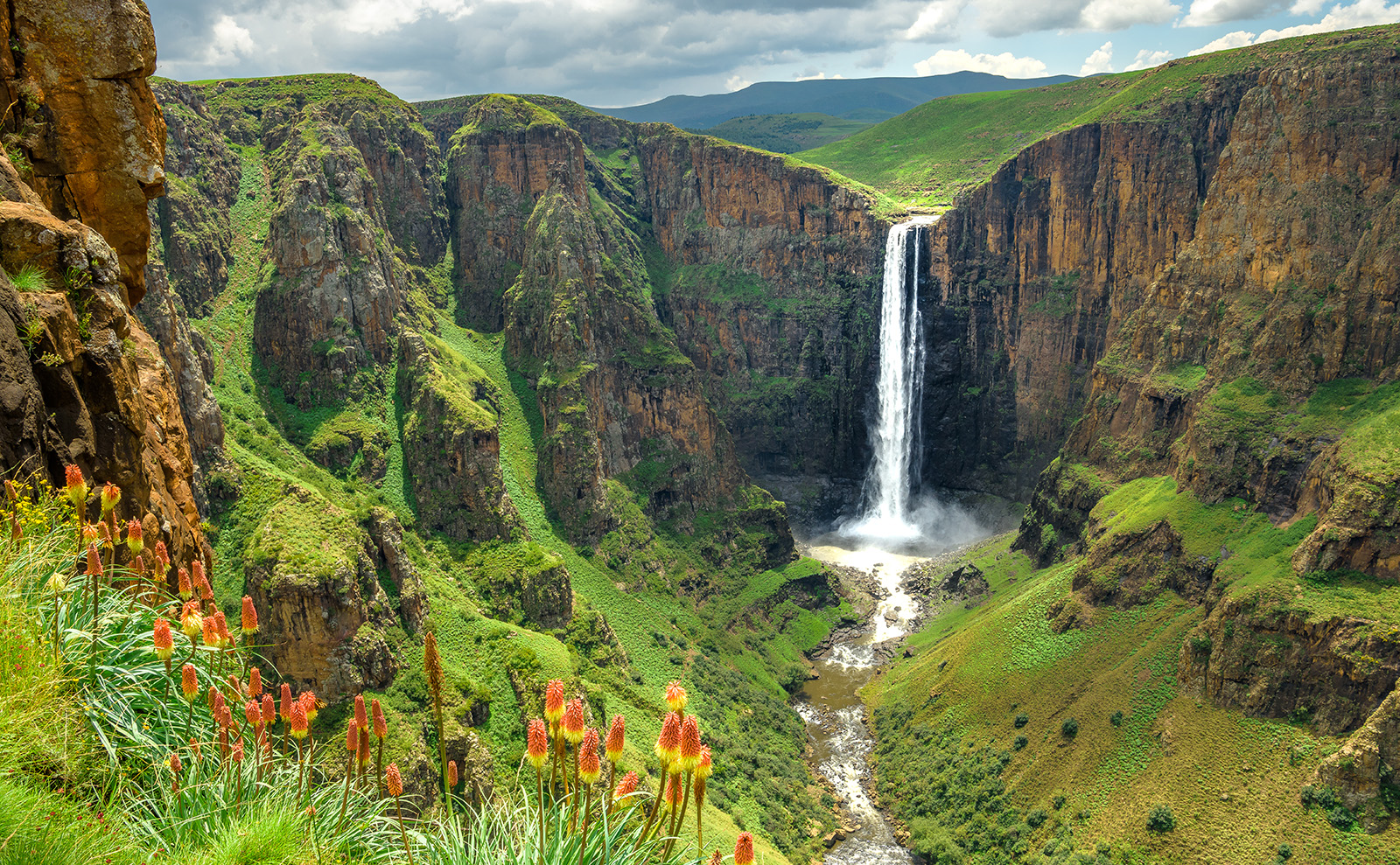 green flat-top mountains with a waterfall tumbling down the rock face
