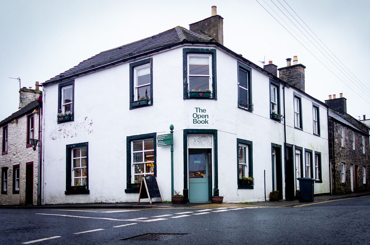 a white building with a green door that says open book