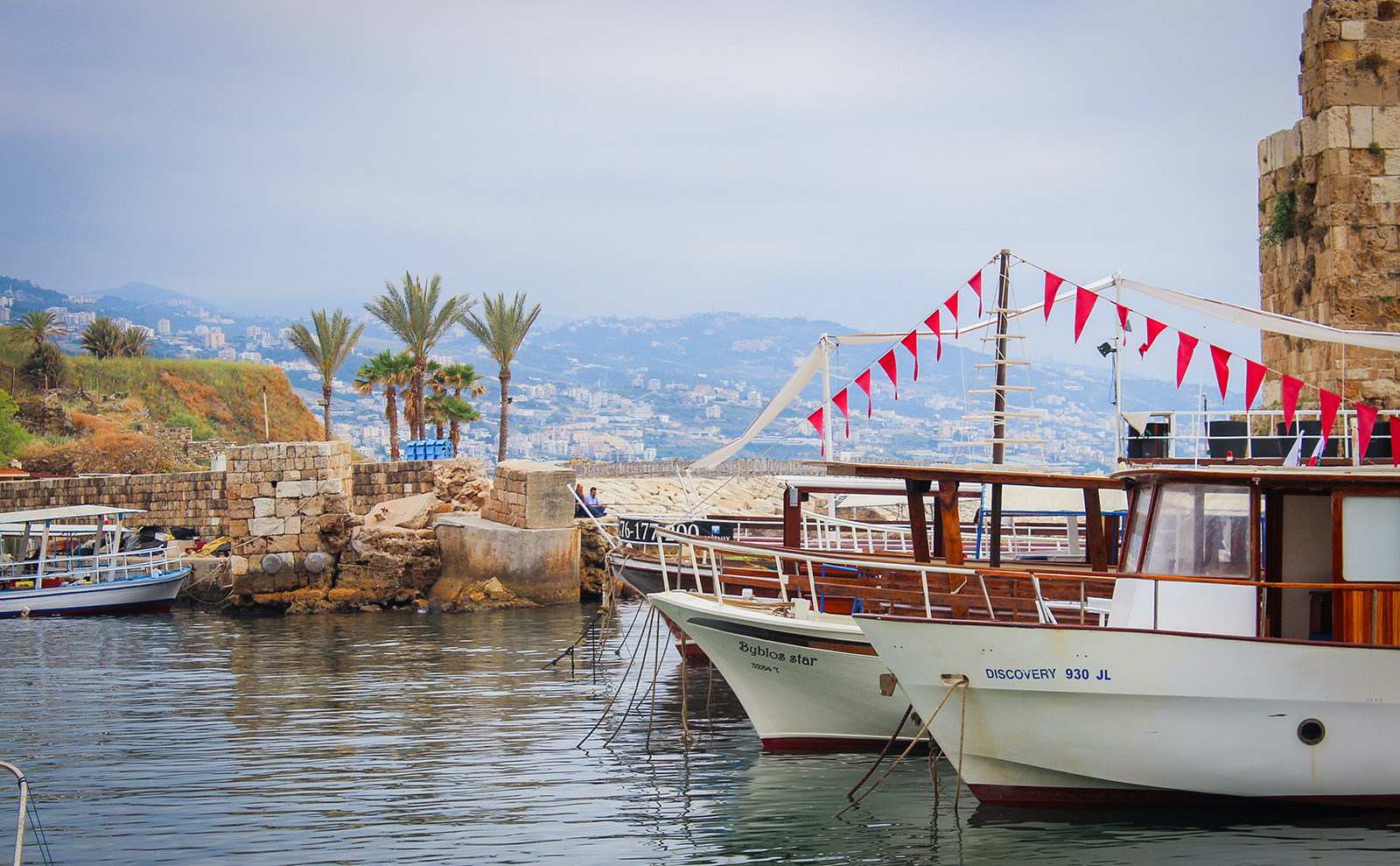 boats moored at a stone pier next to the mediterranean sea