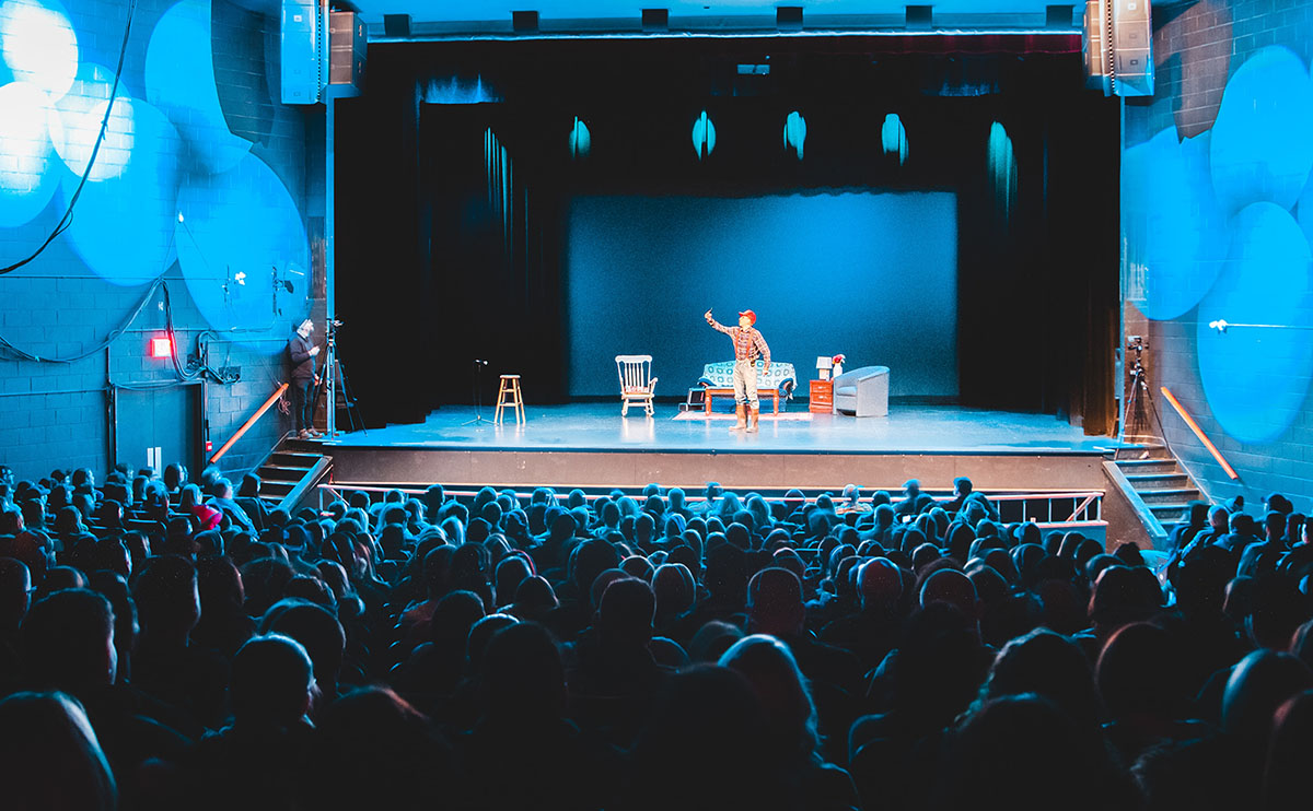 an actor on stage alone with blue lighting