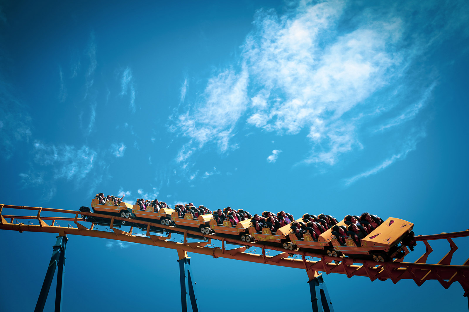 yellow steel roller coaster against a bright blue sky