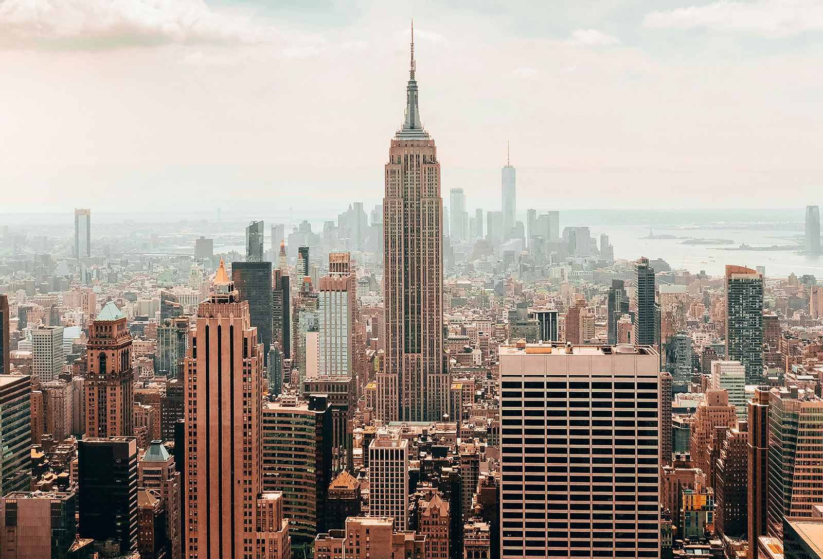 new york city skyline on a sunny day with the art deco empire state building in the center