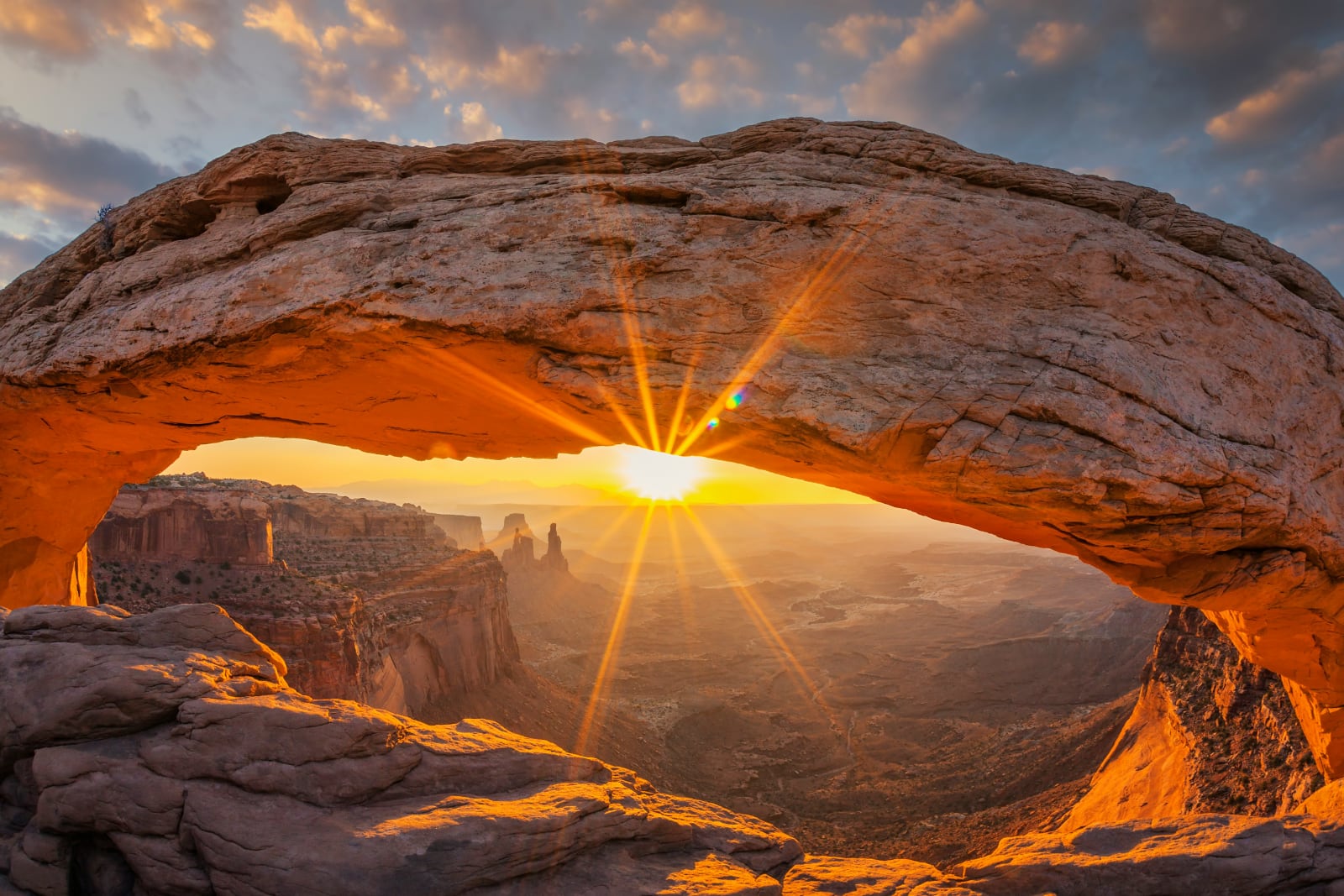 red rock arch with the sun shining under the arch