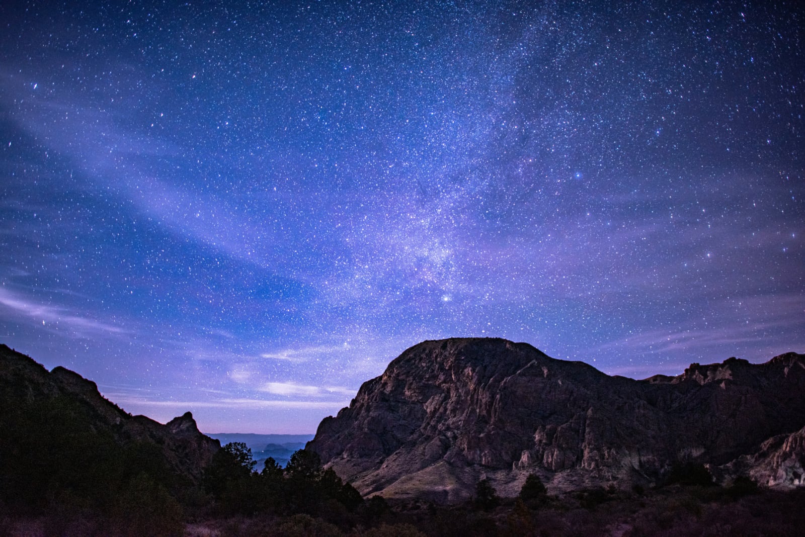 blue and purple sky filled with stars above large craggy rock formations
