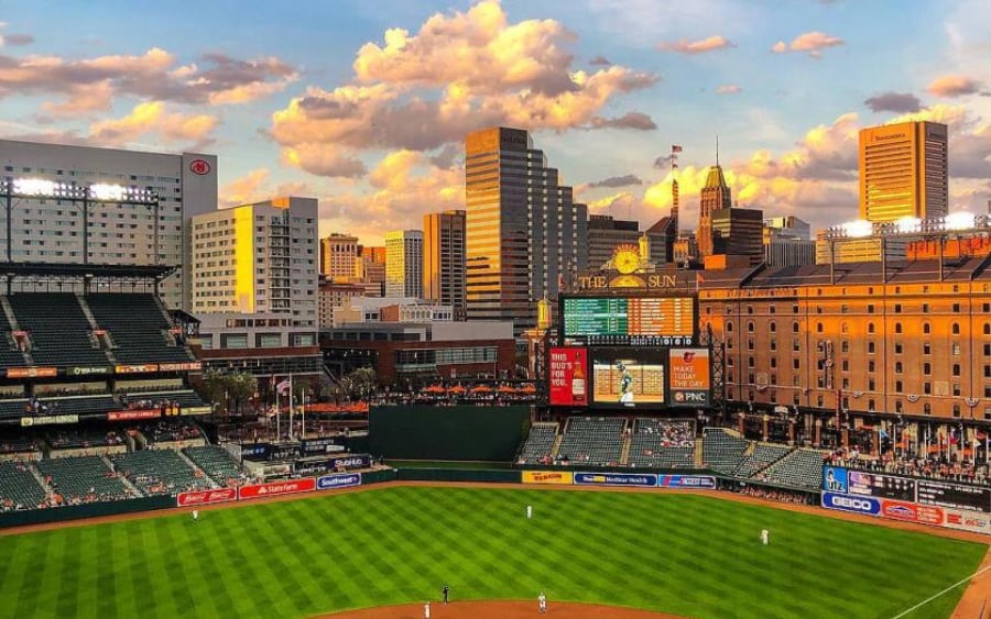 emerald green baseball field under a blue sky that looks like a watercolor painting