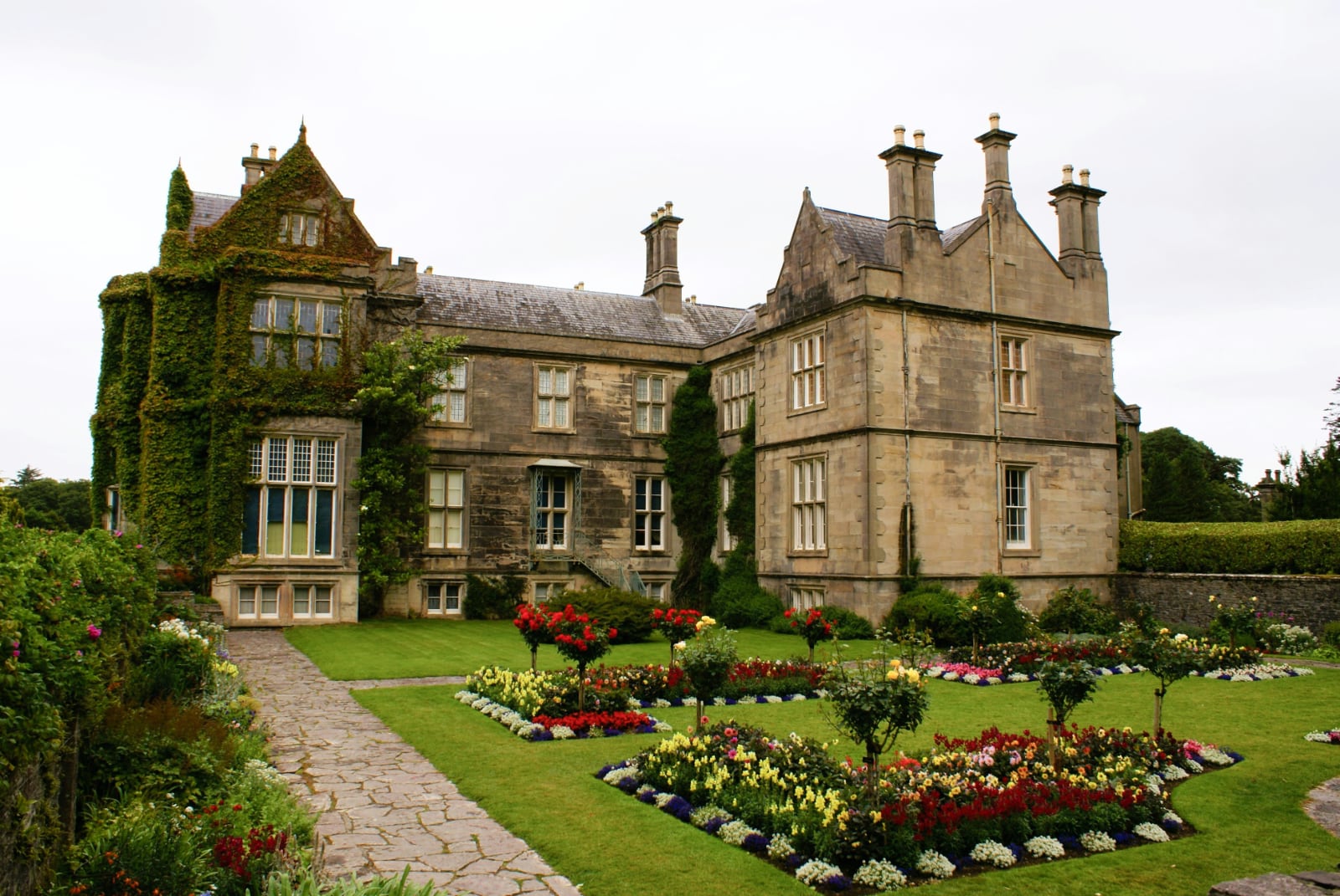 imposing yellow stone house with a colorful manicured garden