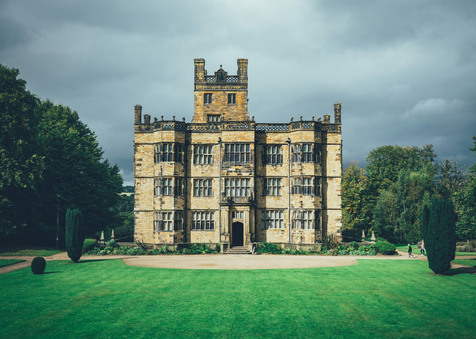 imposing yellow stone house with a wide green lawn under a blue cloudless sky