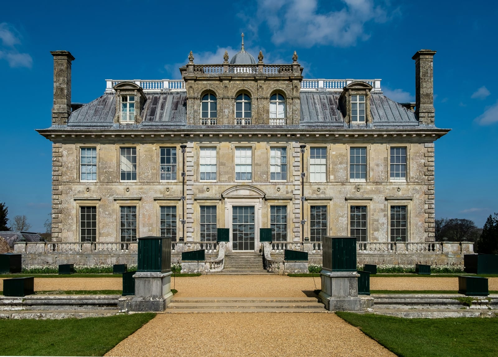 imposing gray stone house with a wide green lawn under a blue cloudless sky