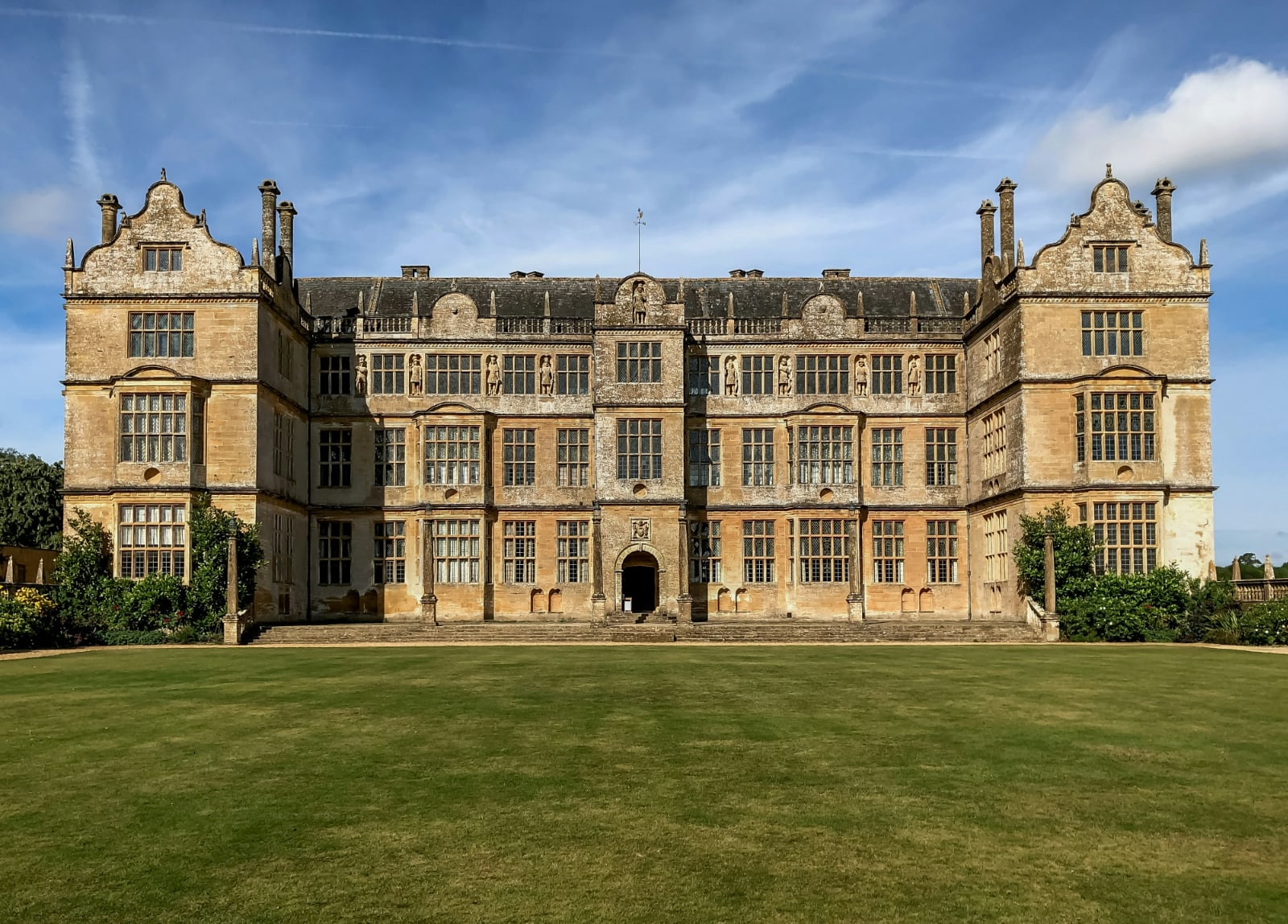imposing brown stone house with a wide dark green lawn