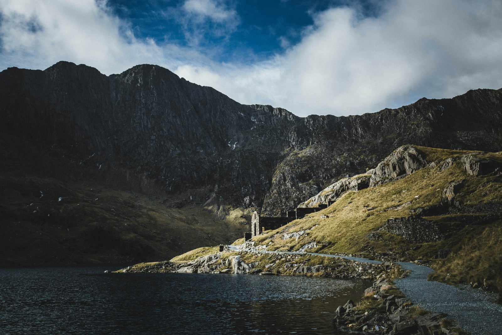 ruins of a stone building in a valley next to a lake