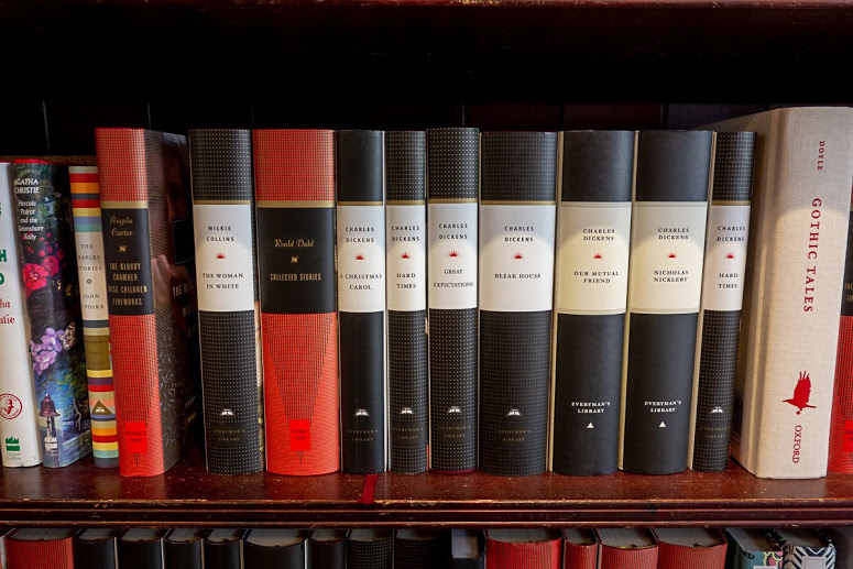 a bookshelf of gray and bold books at Daunt Books