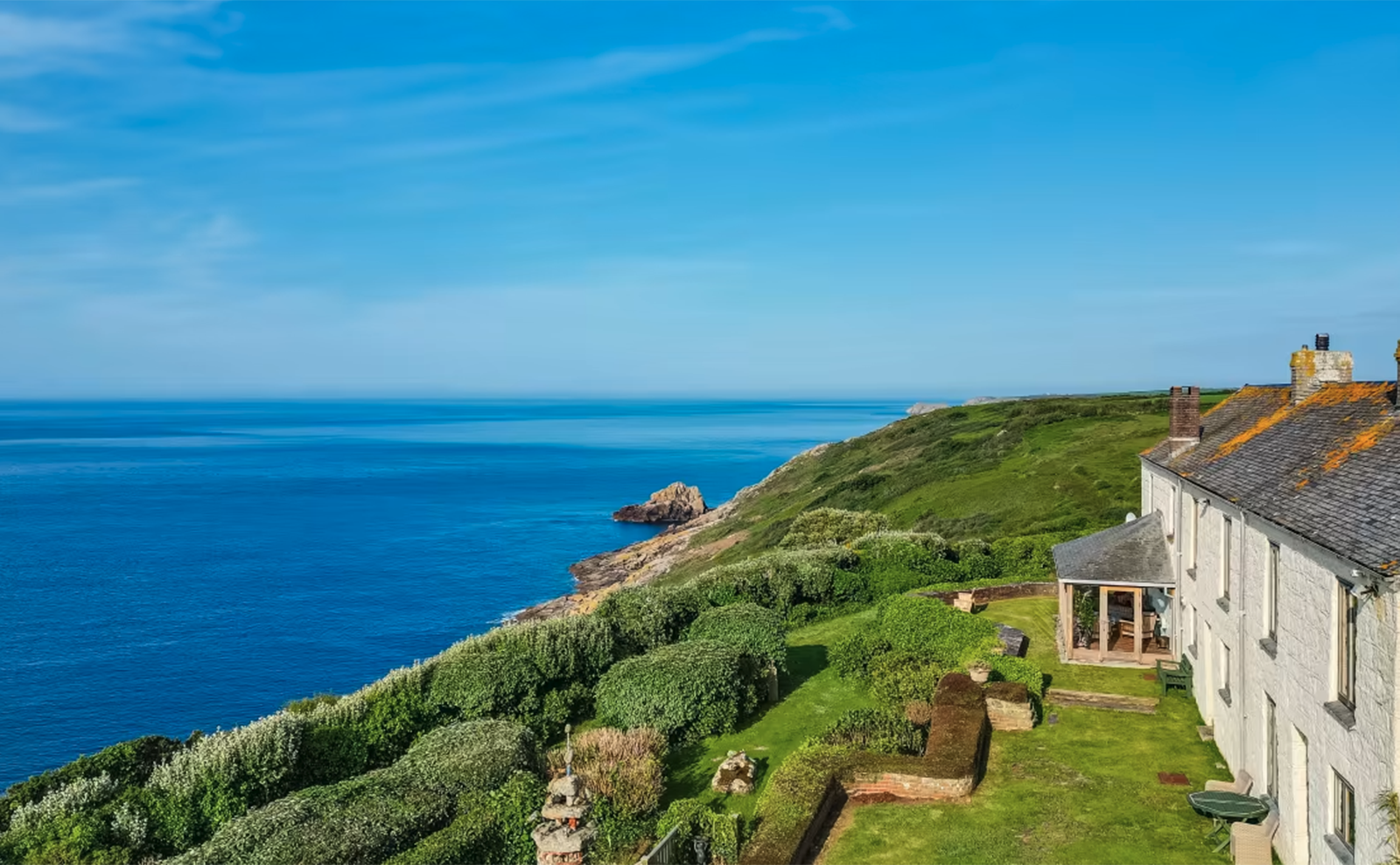  white stone house overlooking the ocean on a green grassy hill