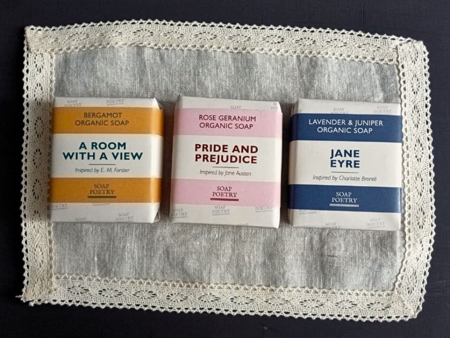 three bars of soap in striped packaging arranged on a piece of lace fabric