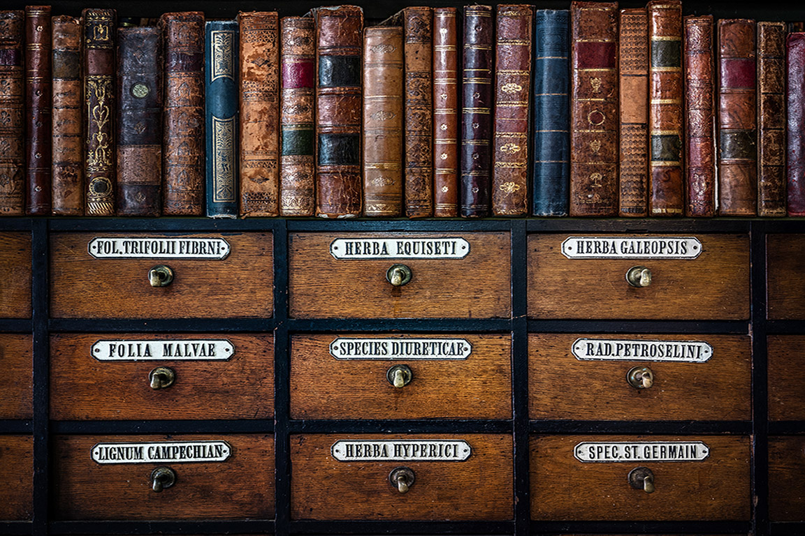antique books piled on top of a wooden card catalog