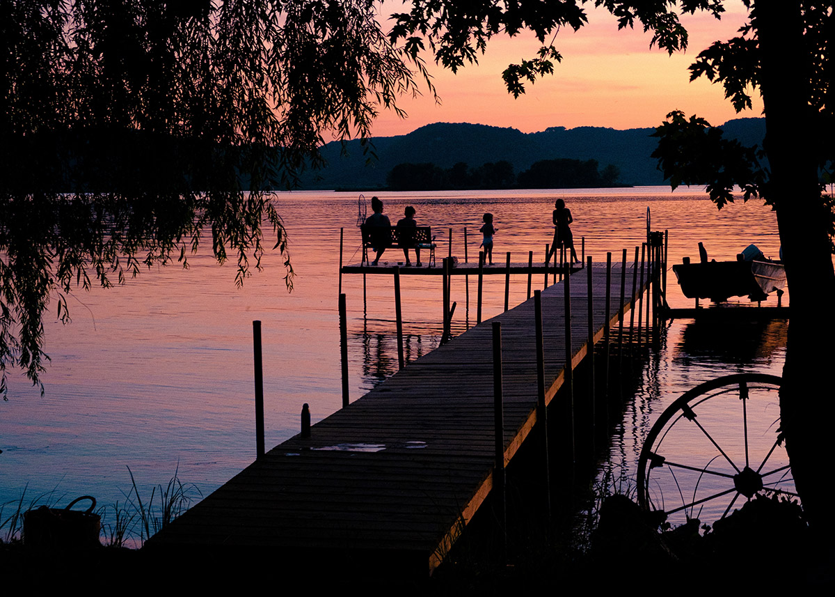 pink sky at sunset over a dock with people in silhouette along the coast of mississippi