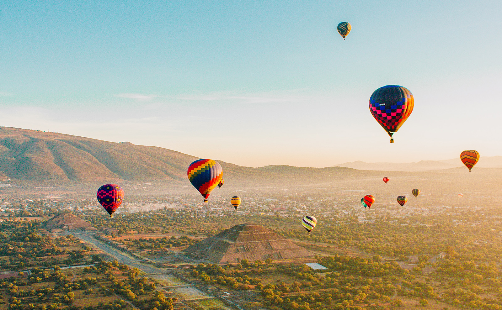 hot air balloons floating over Mayan pyramids