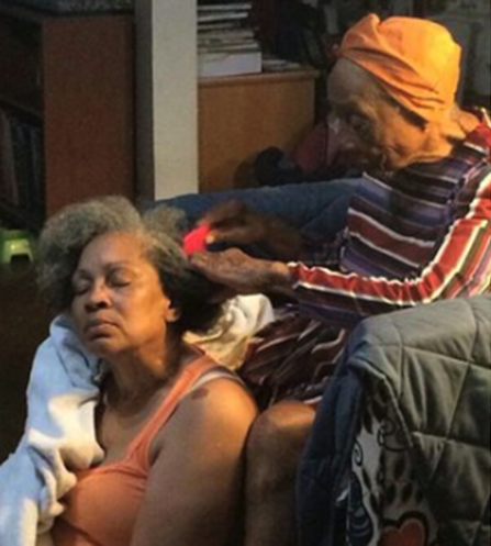 photograph of elderly woman combing another woman's hair