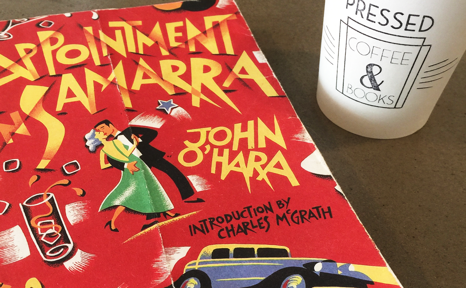 paper cup of coffee and paperback book on a concrete table