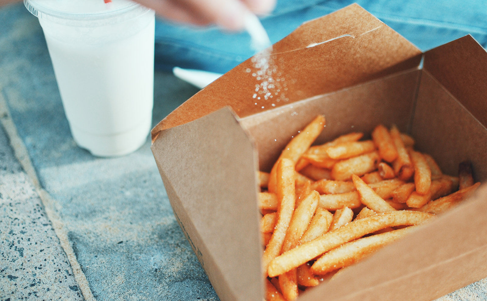basket of french fries being sprinkled with salt