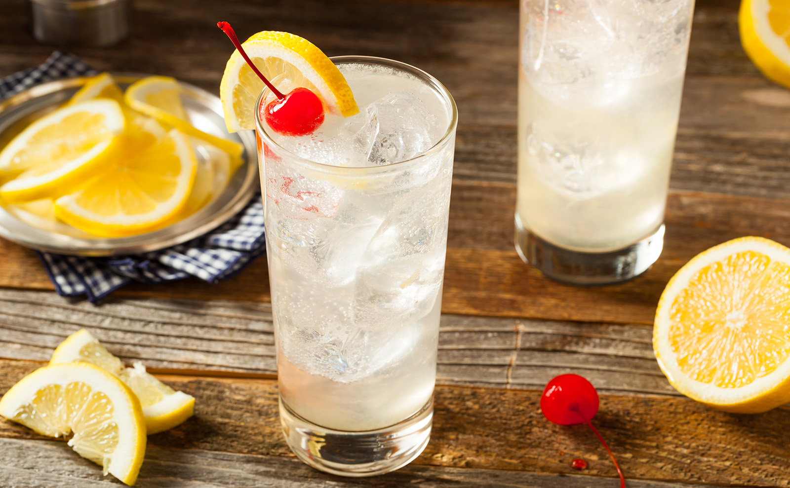 tom collins cocktail sitting on a wooden bar